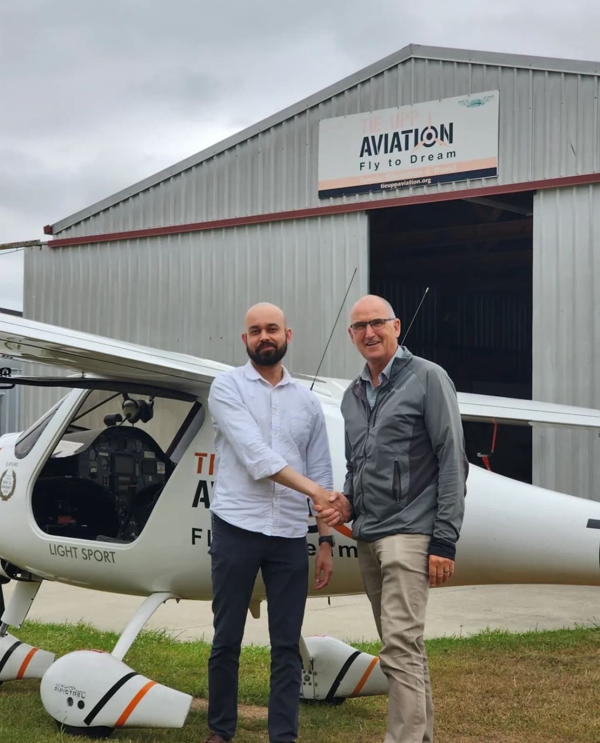 Two pilots shaking hands in front of aircraft